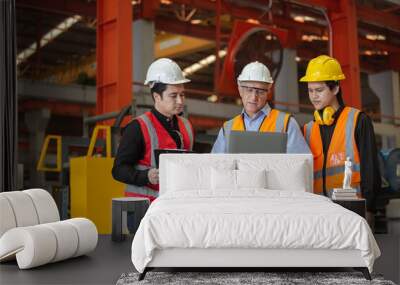 Three man industrial engineers wear hard hats and uniform using laptop talking project of factory inside heavy industry manufacturing. Supervisor teaching work to employee. Wall mural