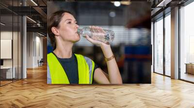 women engineer drinking water from plastic bottle after working at factory during break. drinking pu Wall mural