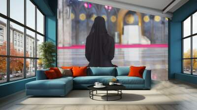 Young muslim woman in wear black dress sitting alone in mosque, Rear view. Wall mural