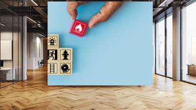 Hand choose cube wooden block stack with fire icon and door exit sing or fire escape with prevent icon and fire extinguisher and emergency prevention or protection symbol for safety and rescue. Wall mural