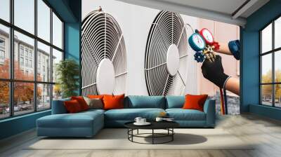 Heat and Air Conditioning, HVAC system service technician using measuring manifold gauge checking refrigerant and filling industrial air conditioner after duct cleaning maintenance outdoor compressor. Wall mural