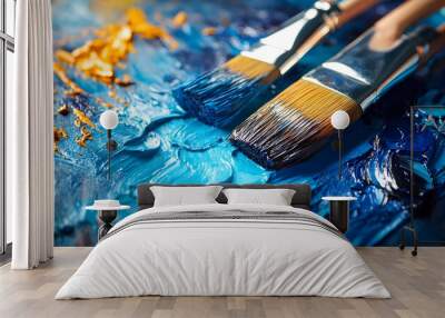 Artistic brushes resting on vibrant blue paint with golden accents, showcasing texture and creativity. Wall mural