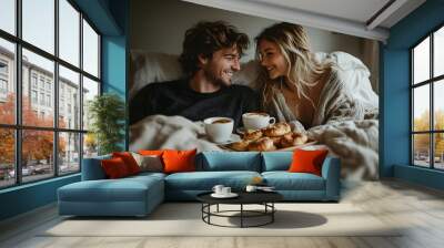 Cozy couple enjoying breakfast in bed with coffee and pastries, sharing laughter and love in a warm, intimate setting. Wall mural