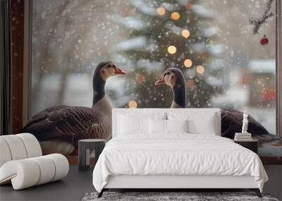 Two geese sit by a window, surrounded by falling snow and holiday lights, capturing a cozy winter atmosphere. Wall mural