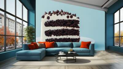 Piece of chocolate cake with vanilla cream and chocolate chips on blue pastel background with copy space Wall mural