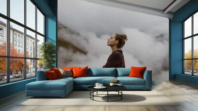 Woman above the clouds in the mountains Wall mural