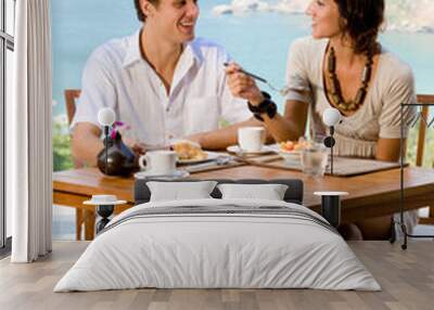 A young couple enjoying breakfast outside with an ocean backdrop Wall mural