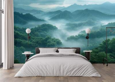 A panoramic view of a mountain range shrouded in mist. The fog flows through the valleys, creating a ethereal and peaceful atmosphere.  Wall mural