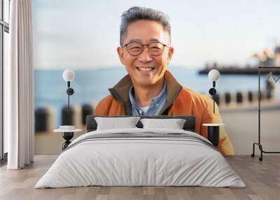 Portrait of happy asian senior man smiling at the seaside Wall mural