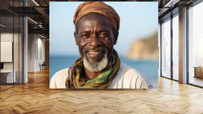 Portrait of smiling mature African man with headscarf standing at beach Wall mural