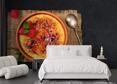 Creme brulee dessert of cream and cane sugar with fresh raspberries and mint leaves on a dark table, layout with copy space. Delicious desserts in a cafe or restaurant Wall mural