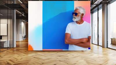 Elderly man with white beard and sunglasses stands in casual pose against colorful geometric pattern background, art portrait and clothing advertisement Wall mural