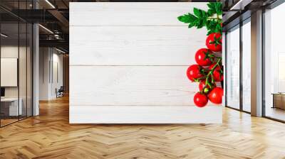 Fresh cherry tomatoes on a branch with leaves in the upper right corner on a white vintage wooden background. Ripe tomatoes in droplets of water. Copy space for text, flat lay. Wall mural