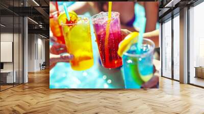 Glasses of lemonade in the hands of friends against the backdrop of the pool, a student party in the pool, the idea of a summer vacation and meeting, advertising refreshing lemonades and juices Wall mural