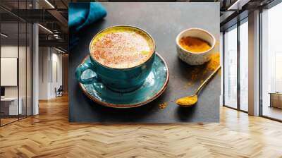 Closeup view of turmeric latte cup on a textured dark background. Wall mural