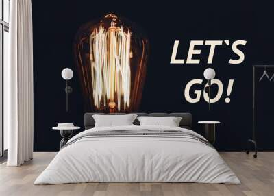 Inscription Let's go on the image of retro bulb on a black background. Motivation concept. Wall mural