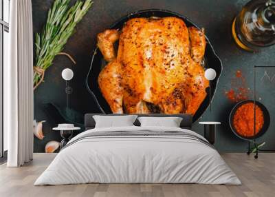 Roasted whole chicken with spices in a black iron skillet on a table. Wall mural