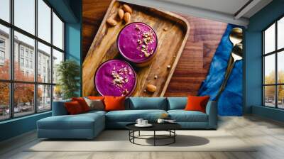 Top view of two glasses with violet berry smoothie are served crushed almond on a wooden tray. Wall mural