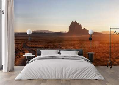 Striking panoramic landscape view of a dirt road in the dry desert with a mountain peak in the background during a vibrant sunset. Taken at Shiprock, New Mexico, United States. Wall mural