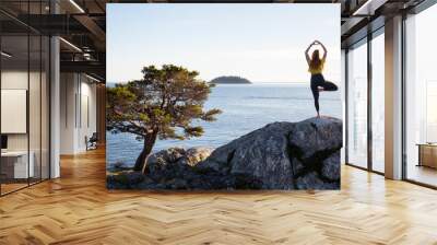 Young woman practicing yoga on a rocky island during a vibrant sunset. Taken in Whytecliff Park, Horseshoe Bay, West Vancouver, British Columbia, Canada. Wall mural