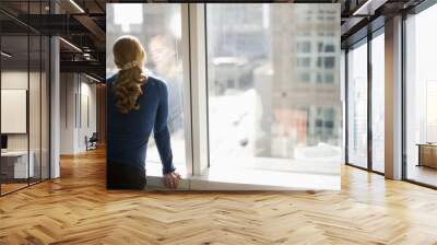 businesswoman looking out office window Wall mural