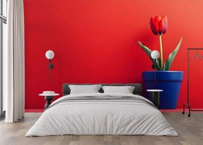 A single red tulip in a blue pot against a bright red background. Wall mural