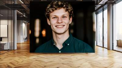 A young man with curly blond hair smiles warmly at the camera. Wall mural