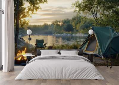 Camping by a lake at sunset with a tent, fire, and a chair. Wall mural