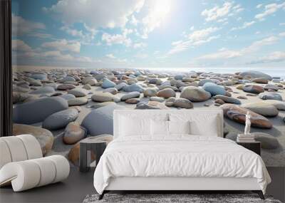 Smooth, colorful river rocks on a sandy beach, under a bright blue sky with puffy clouds. Wall mural