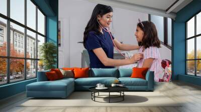 Close-up of a Mexican doctor checking a little girl with her stethoscope. Wall mural