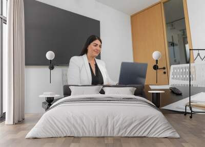 Cropped view of executive woman working in her office smiling, while typing on her laptop Wall mural