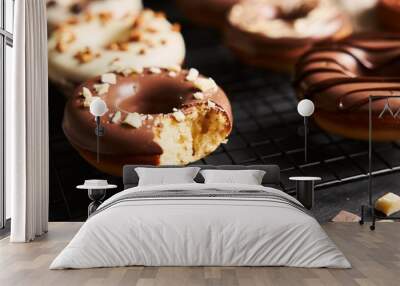 Beautiful shot of a bitten donut covered in the white and brown chocolate glaze on a black table Wall mural