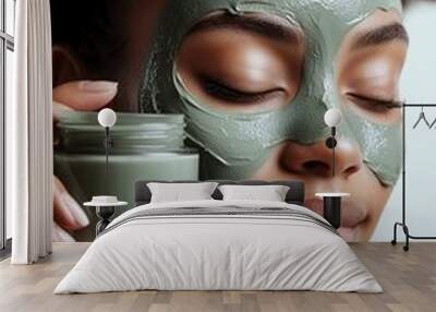 Woman applying facial clay mask, enjoying a skincare routine Wall mural