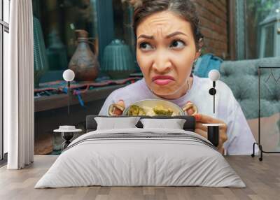 A disgruntled woman face with cauliflower and steamed broccoli. The concept of a boring diet and eating disorders Wall mural