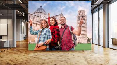 A fun and diverse group of young tourist friends pose against the backdrop of the famous leaning tower in Pisa. Tourism in Italy after canceling the quarantine and lockdown concept Wall mural