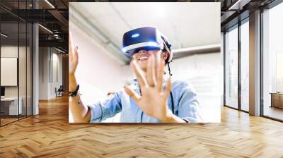 A woman enthusiastically playing or working in the helmet of virtual reality VR. Wall mural