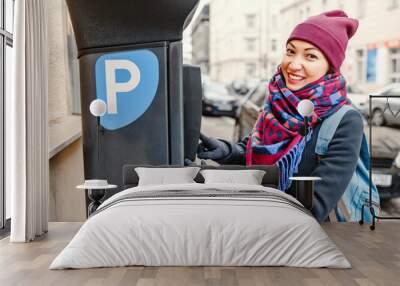 A woman pays for parking her car in an automated terminal of a parkomat Wall mural