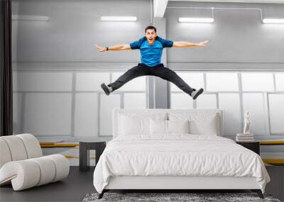 A young fit happy man jumping and flying on trampoline in fitness gym Wall mural