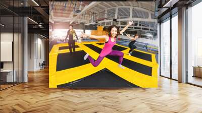 Cheerful and happy woman practicing and jumping on trampolines in a sports indoor center, workout and modern entertainment concept Wall mural