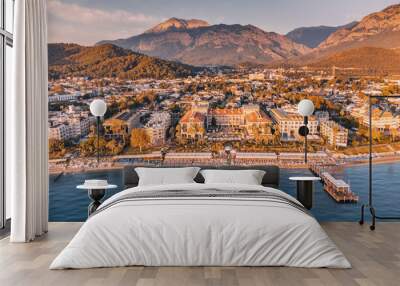 Discover a slice of paradise with striking aerial view, capturing the perfect blend of relaxation and natural wonder in Kemer, featuring hotels, a serene sea beach, and majestic mountains. Wall mural