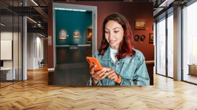 Girl uses the application on her smartphone as an audio guide and a virtual tour of the Museum of Fine Arts and an exhibition of paintings. Wall mural