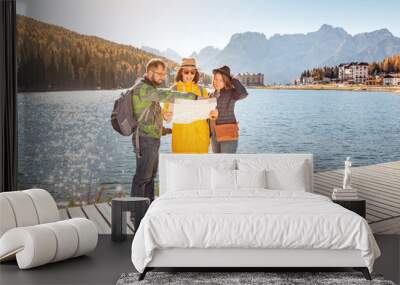 Group of Friends travelers searching right direction on map, standing at the coast of a famous Misurina lake in Tyrol, Italian Dolomites mountains Wall mural