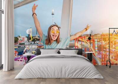 Happy and excited asian girl riding ferris wheel in amusement park Wall mural