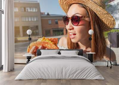 Happy asian girl eating taco outside. Mexican fastfood cuisine. Tasty and spicy snack in park Wall mural