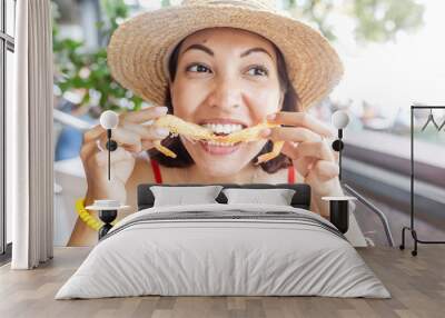 Happy Asian woman in hat eating local Spanish cuisine grilled seafood and prawns Wall mural