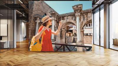 traveler with a toy plane on the background of the archaeological monument - the gate of the Emperor Hadrian in the old city of Antalya. Concept of air tickets and airlines in Turkey Wall mural