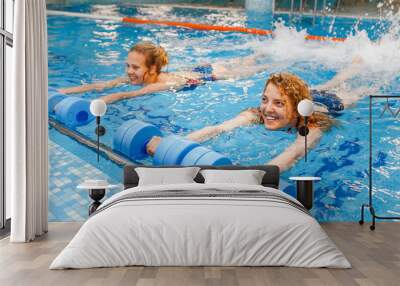 two happy girls exercising in swimming pool with dumbbells. aqua aerobics classes concept Wall mural