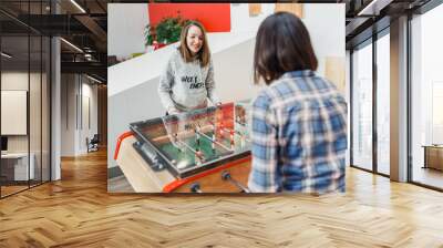 Two happy women friends playing table football at leisure time Wall mural