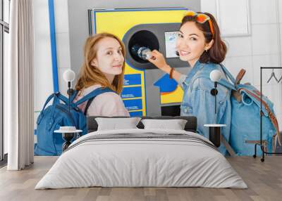 woman friends together at the reverse vending machine recycle plastic bottles, ecology concept Wall mural