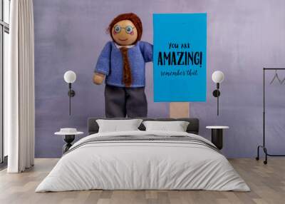 Colorful wooden toy man holding a blue sign with a positive quote, promoting self-belief and joy in a delightful and playful atmosphere Wall mural